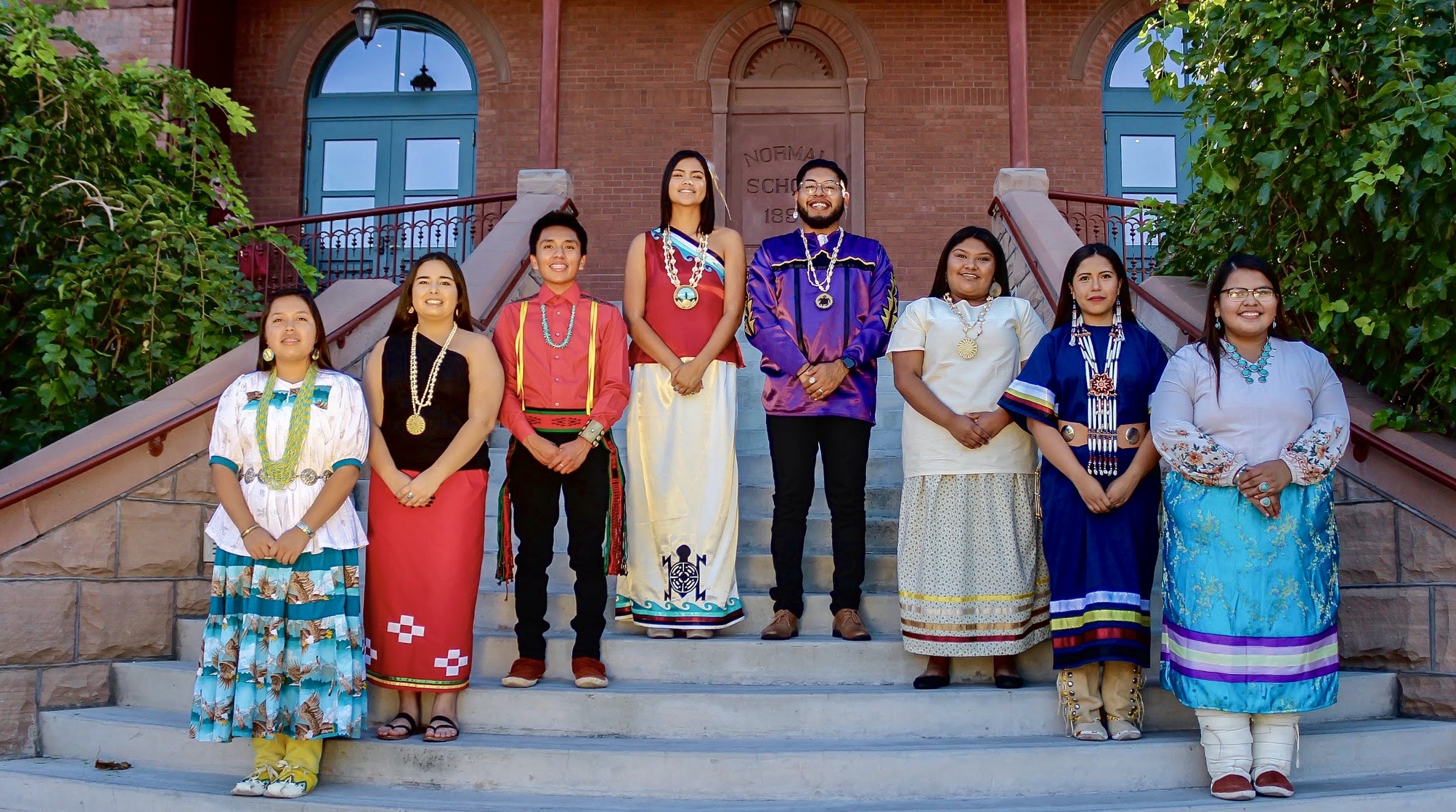 eight American Indian students standing on steps in varying traditional clothing